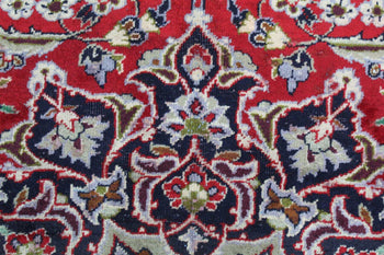 A close-up view of a traditional Persian rug showcasing intricate floral and geometric patterns with a dominant red background interspersed with blues, creams, and hints of green homelooks.com