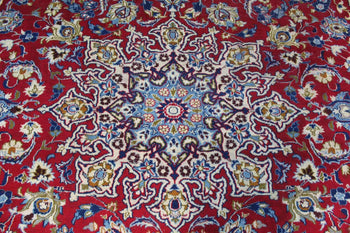 Detailed view of the central medallion design on a red oriental rug with blue and cream accents homelooks.com