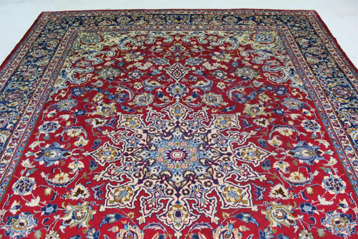 Ornate Persian rug with a rich red field and intricate floral and geometric patterns in blue, white, and gold hues, showcasing a detailed central medallion. homelooks.com