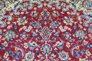 Close-up of a Persian rug detailing the intricate floral motifs and complex geometric designs in vibrant blue, red, and cream colors on a deep red background. homelooks.com