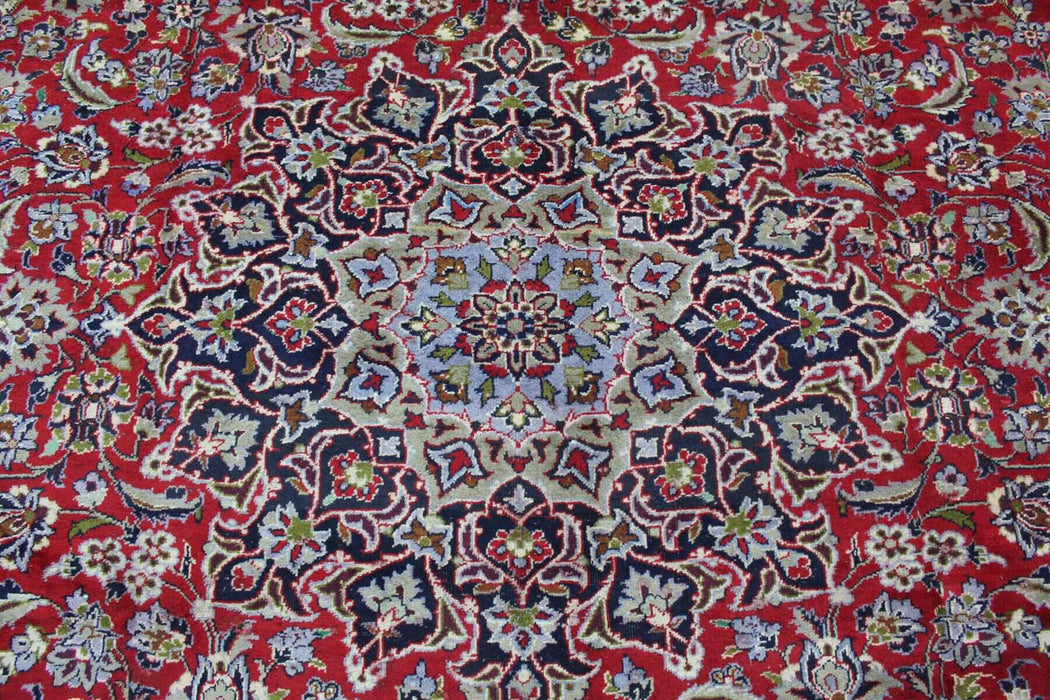 An ornate Persian rug with detailed border designs and a complex central medallion, featuring a blend of red, blue, beige, and dark accents. homelooks.com